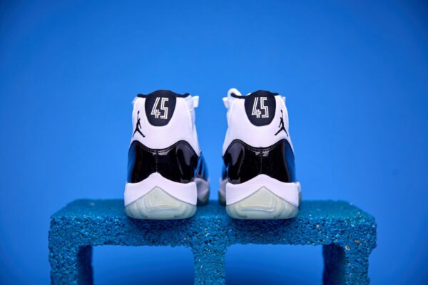 Air Jordan 11 High preto e branco, com couro envernizado brilhante, solado translúcido e o icônico logotipo Jumpman na lateral, visto de perfil