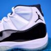 Air Jordan 11 High preto e branco, com couro envernizado brilhante, solado translúcido e o icônico logotipo Jumpman na lateral, visto de perfil