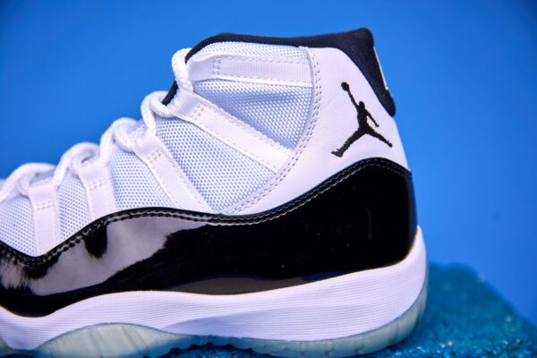 Air Jordan 11 High preto e branco, com couro envernizado brilhante, solado translúcido e o icônico logotipo Jumpman na lateral, visto de perfil