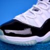 Air Jordan 11 High preto e branco, com couro envernizado brilhante, solado translúcido e o icônico logotipo Jumpman na lateral, visto de perfil