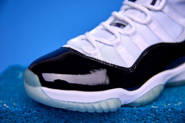 Air Jordan 11 High preto e branco, com couro envernizado brilhante, solado translúcido e o icônico logotipo Jumpman na lateral, visto de perfil