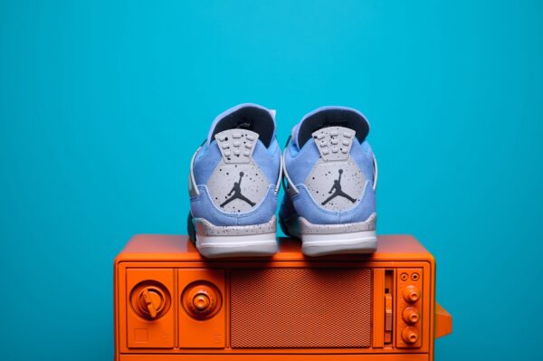 Nike Air Jordan 4, destacando os painéis laterais em mesh, a entressola robusta e os detalhes clássicos do modelo.