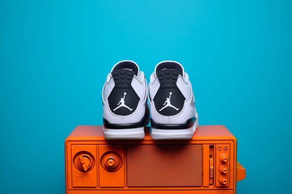 Nike Air Jordan 4, destacando os painéis laterais em mesh, a entressola robusta e os detalhes clássicos do modelo.