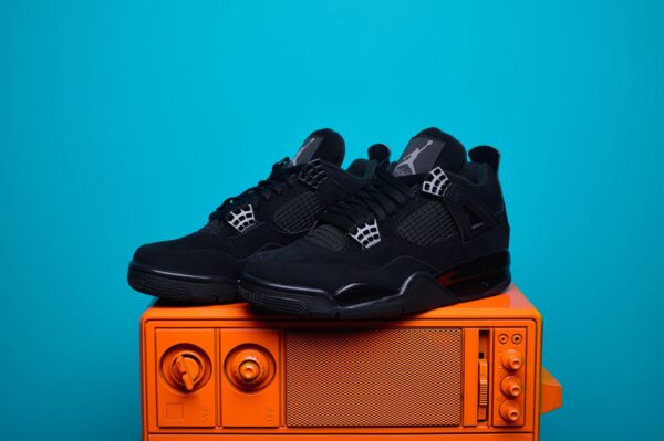Nike Air Jordan 4, destacando os painéis laterais em mesh, a entressola robusta e os detalhes clássicos do modelo.