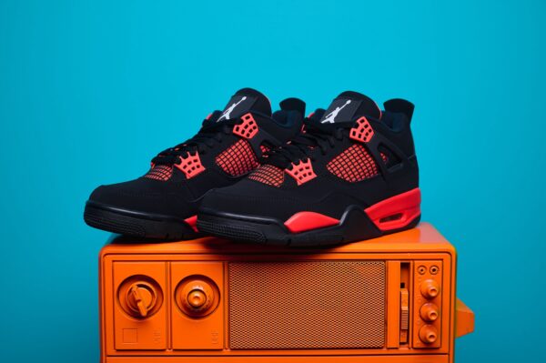 Nike Air Jordan 4, destacando os painéis laterais em mesh, a entressola robusta e os detalhes clássicos do modelo.