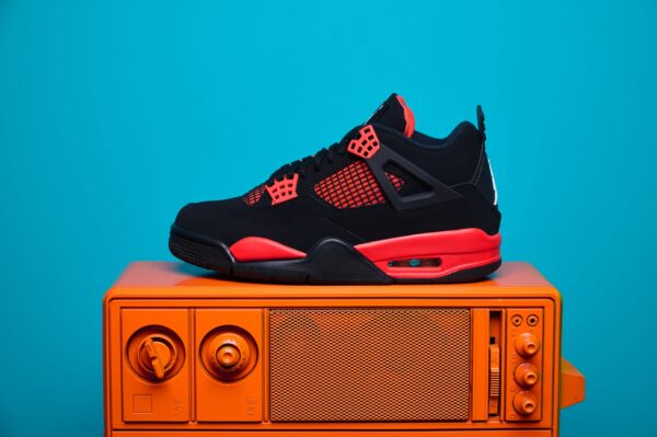 Nike Air Jordan 4, destacando os painéis laterais em mesh, a entressola robusta e os detalhes clássicos do modelo.
