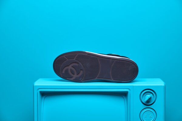 Tênis Chanel de couro e camurça, com logo icônico e design moderno e sofisticado. Solado robusto para conforto e estilo refinado.