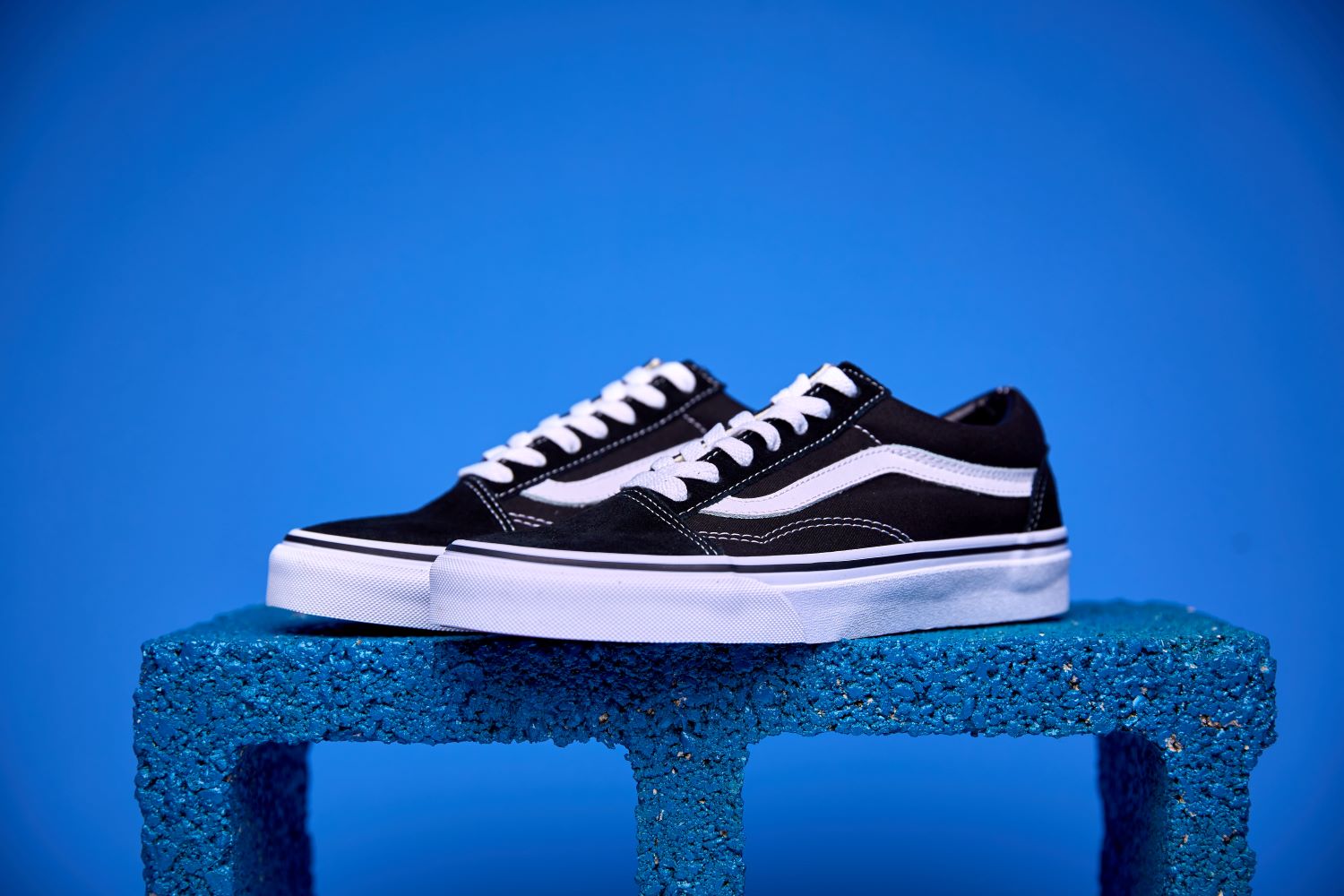 Tênis Vans Old Skool preto e branco, com a icônica faixa lateral e solado Waffle antiderrapante.